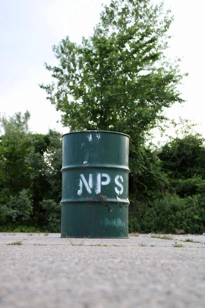 A green plastic barrel near the trees