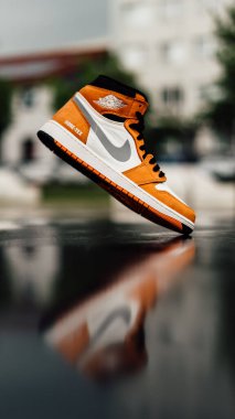 Beyaz ve turuncu Nike Air Jordan 'ın dikey ve sığ odak görüntüsü.