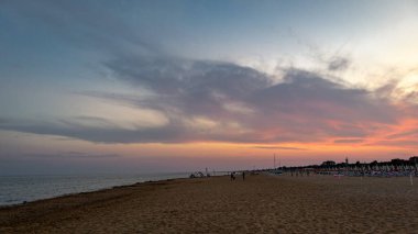 Gün batımında kumlu sahilin manzarası. Güverte sandalyeleri ve şemsiyelerle.