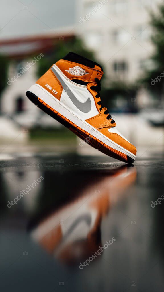 A vertical shallow focus shot of white and orange Nike Air Jordan I sneaker