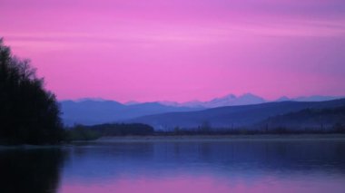 Romanya 'nın Valcelele kentinde gölün üzerindeki pembe günbatımının manzarası
