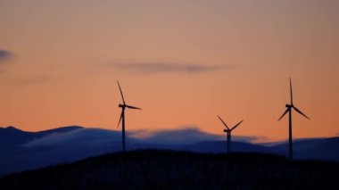 İsveç, Kiruna 'da, gün batımında İskandinavya' da bir tepenin üzerindeki yel değirmenlerinin manzarası.