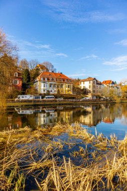 İlkbaharda Almanya 'nın Schmalkalden kentindeki nehre yansıyan canlı binaların dikey çekimi