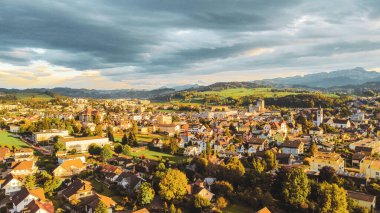 İsviçre 'nin Uzwil şehrinin arka planında yeşil dağların bulunduğu güzel bir şehir manzarası.
