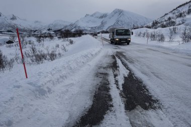 Norveç 'in Lofoten Adaları' ndaki karlı dağlarda buzlu bir patikada beyaz bir kamyon.