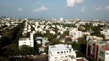 Gökyüzünün altında beyaz binalar ve ağaçlar olan bir şehrin insansız hava aracı videosu.