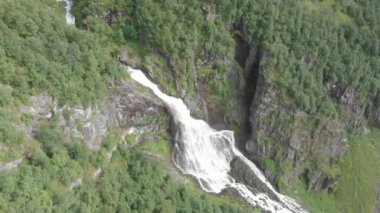 Norveç, İskandinavya 'nın dağlarındaki uçurumlardan akan büyük bir şelaleden tepeden aşağı insansız hava aracı görüntüsü
