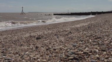Dovercourt plajında ileri geri giden kirli dalgalarla dolu bir sahilin yavaş çekimi.