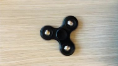 Tahta bir masada dönen siyah bir parmak fırıldağının yavaş çekim videosu..