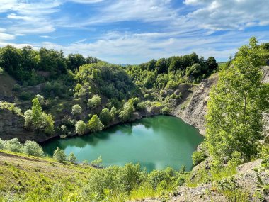 Kayalık dağlar ve ağaçlarla çevrili küçük sakin bir göl.