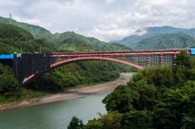 Tayvan 'daki yeşil dağlarla çevrili nehrin üzerindeki Luofu Köprüsü manzarası.