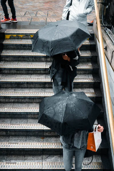 英国伦敦 一张垂直拍摄的拿着雨伞走下楼梯的人的照片 — 图库照片