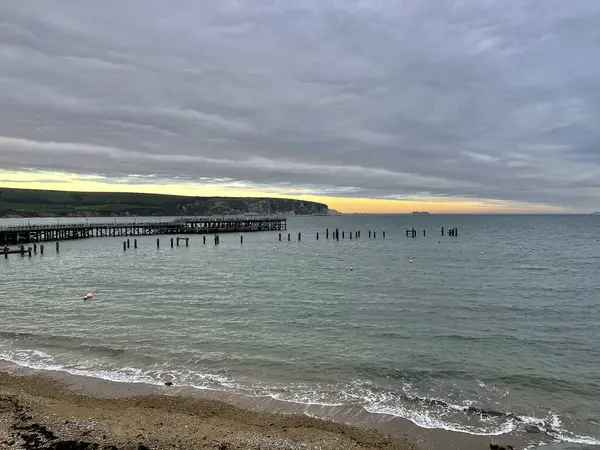 Schöne Aussicht Auf Einen Strand Mit Pier Unter Wolkenverhangenem Himmel — Stockfoto