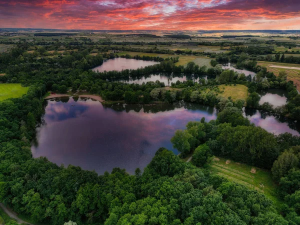 夕焼け空の下 緑の木々に囲まれた小さな湖 — ストック写真