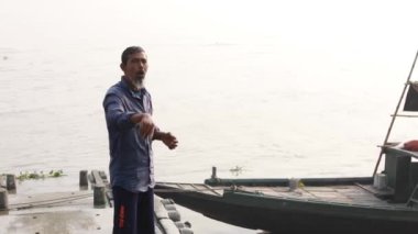 Bengalce konuşan kimliği belirsiz bir tekne operatörü, turistlere Taki 'deki Ichamati Nehri' ndeki teknesine inmelerini söylüyor.