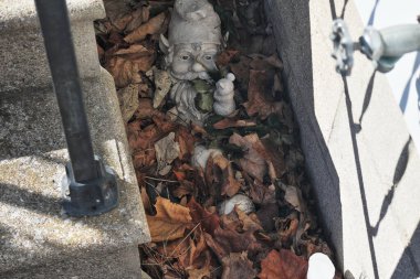 Sonbahar kuru yapraklarıyla kaplı küçük cüce heykeli.