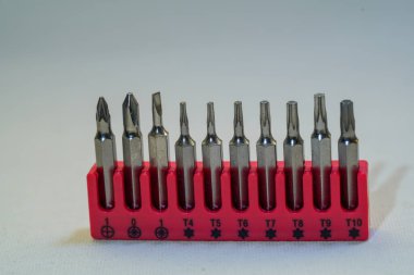 Sade bir arka planda, kırmızı stantlarında farklı boyutlarda tornavida setinin yakın çekimi.