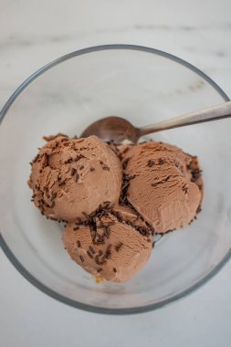 Bir kasede üç kepçe çikolatalı dondurmanın dikey görüntüsü.
