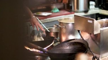 Mutfaktaki ateşin üstünde tavayla yemek yapan bir adam.