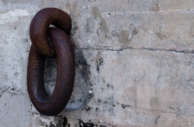 Gri taştan bir duvardaki paslı, kalın metal halkaların yakın plan çekimi.