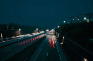 Gece vakti bir otoyolda uzun pozlu araba ışıkları.