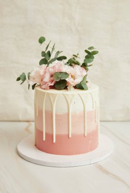 Pembe çiçekler ve yeşillikle süslenmiş pasta.