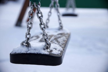 Çocuk parkındaki karla kaplı salıncağın yakın çekimi.