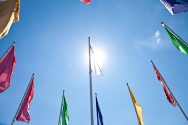 Mavi gökyüzündeki direkler üzerindeki renkli bayrakların alçak açılı çekimi