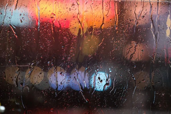 雨天雨点灯背景下潮湿的窗户表面的特写 — 图库照片