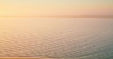 Gün doğumunda berrak gökyüzünün altında sakin bir denizin güzel manzarası.