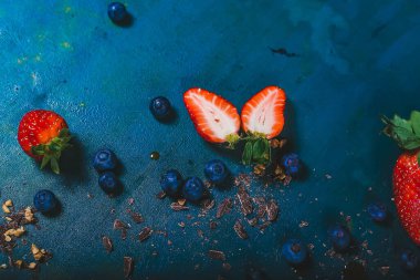 Mavi bir yüzey üzerinde taze çilek ve yaban mersini manzarası