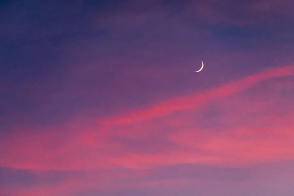 A beautiful crescent moon in a purple pink night sky