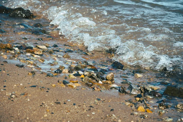 在波涛汹涌的沙滩上的小石头的特写 — 图库照片
