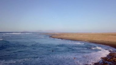 Kanarya Adaları, Fuerteventura Adası, Majanicho 'da sörf yapan insanların insansız hava aracı görüntüleri.