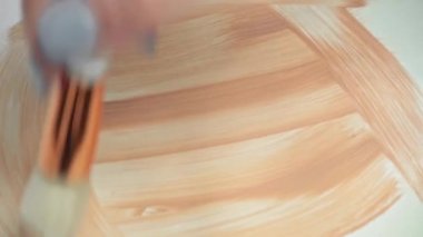 Beyaz tuval üzerinde bej boya ile rastgele fırça darbelerinin görüntüsü