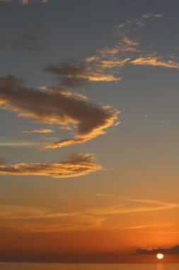 Deniz üzerinde parlak bir günbatımının dikey görüntüsü.