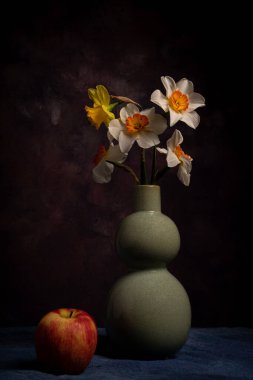 Flowers in vase beside red apple