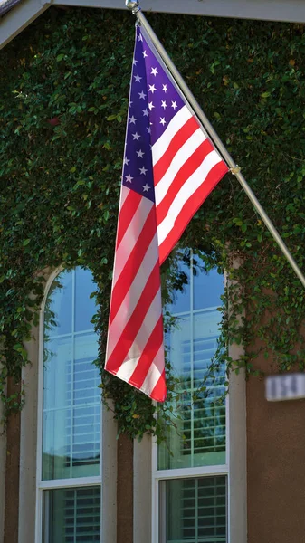 A vertical shot of a hanging American flag on a pole
