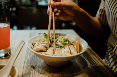 Lezzetli et ve çubuklu sebzeli ramen yiyen biri.