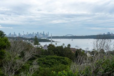 Avustralya 'daki mavi deniz ve şehir manzarasına karşı yeşil bir manzaranın yüksek açılı görüntüsü.