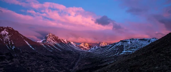 粉红云彩日落天空背景下的雪帽岩石全景 — 图库照片