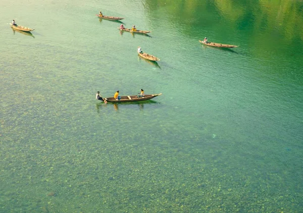 澄んだ緑の湖に乗っている木製のボートの人々のグループ — ストック写真
