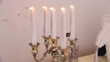 Lüks bir ev dekoru, şamdanda yanan beyaz mumlar ve masanın üzerindeki mürekkep hokkası beyaz bir kalem.