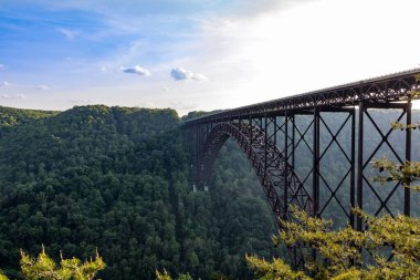 New River Gorge Köprüsü 'nün arka planında yeşil orman olan güzel gökyüzünün altında bir açı çekimi.