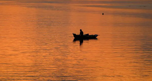 Ένα Άτομο Μια Βάρκα Ένα Ηλιοβασίλεμα Που Αντανακλά Στο Νερό — Φωτογραφία Αρχείου