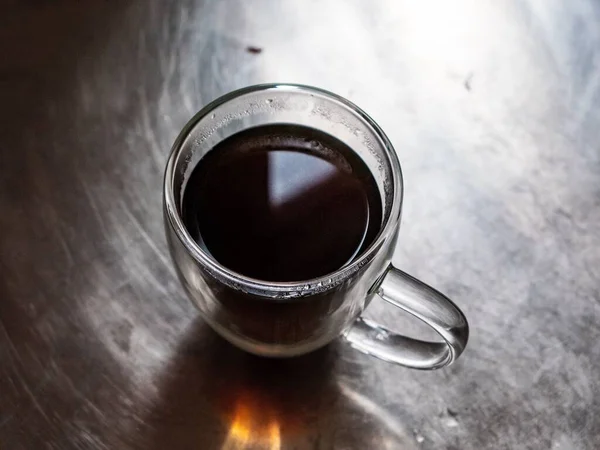 在金属表面的透明杯子中热咖啡的顶景特写 — 图库照片