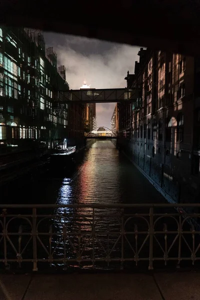 在漆黑的夜晚从一座桥上看到的旧楼之间的一条运河的垂直截图 — 图库照片