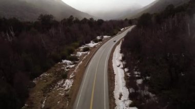 Hafif bir kar yağışı sırasında bir arabanın sürdüğü ormanda uçan bir anten.