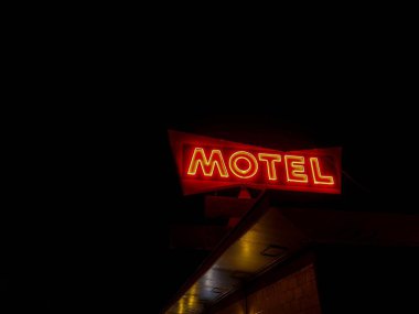 Siyah gökyüzü arka planında kırmızı neon bir motelin düşük açılı görüntüsü.