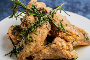 Yakından çekilmiş baharatlı ve biberiye yapraklı kızarmış tavuk kanadı.